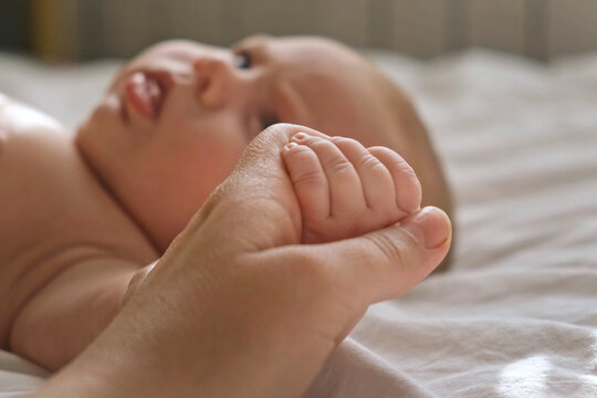 Baby hand in mother hands, on her palm. Happy parents holding their newborn baby tiny fingers, close up. Maternity, family, birth concept. Woman touching hand of infant baby. Mom and her Child