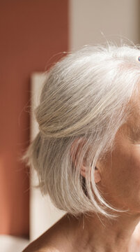 Close-up profile of a senior woman's silver hair texture in soft studio light