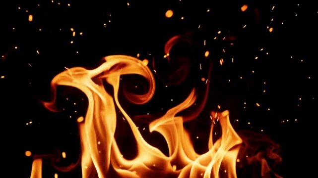 Bright orange flames and glowing embers rising against a dark black background