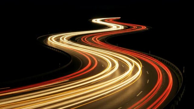 Long exposure light trails of traffic on a winding highway at night