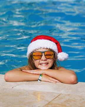 Christmas vacation on a tropical island. A happy girl child at a swimming pool at Christmas. Poster with copy space.
