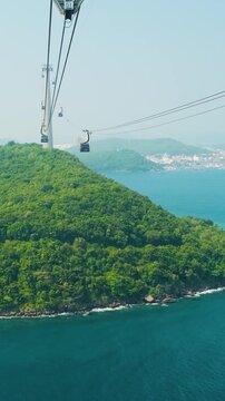 Cable cars travel above lush tropical island and blue sea in Phu Quoc, Vietnam. Island transportation, sustainable tourism infrastructure, island connectivity, destination development 
