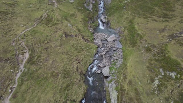 Alpine waterfall and mountain stream in Hohe Tauern national park, Austria, shown in an aerial drone tilt shot