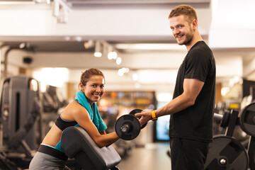 Fototapeta premium happy girl posing with fitness coach lifting weights