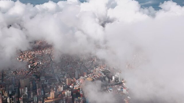 Aerial drone view of dense La Paz cityscape veiled by low clouds in the Bolivian Andes