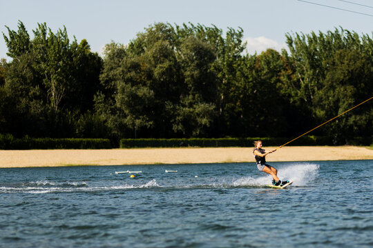 Female wakeboarder wakesurfing. Girl riding waterski cabel. Holding tow rope. Summer activities in the lake.