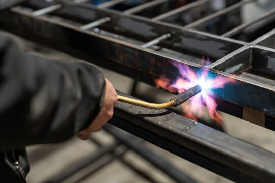 Brazing torch heating a steel profile with pink sparks