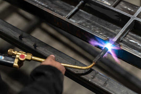 Close up of a brazing torch and blue flame on a steel section
