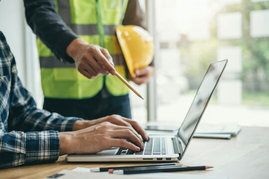 Construction professionals collaborating on a project using a laptop in an office