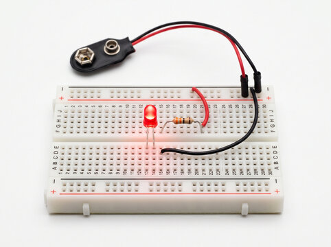 Red led diode connected to resistor and battery terminal on breadboard for circuit testing.