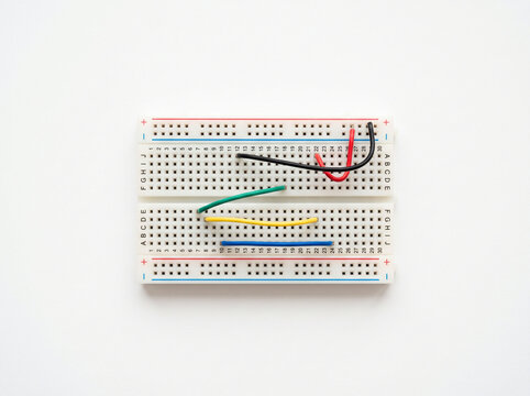 Electronic breadboard prototype with primary colored wires on white background for design.