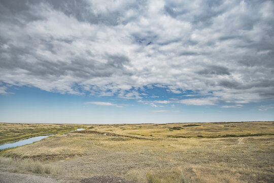 Steppe river flowing through the wild steppes of Kazakhstan in summer under cloudy skies; steppe landscape for background