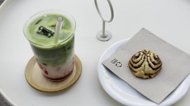 B-Roll: Erfrischender Iced Raspberry Matcha Latte an einem Sommertag und Franzbr&ouml;tchen-Keks im Fokus