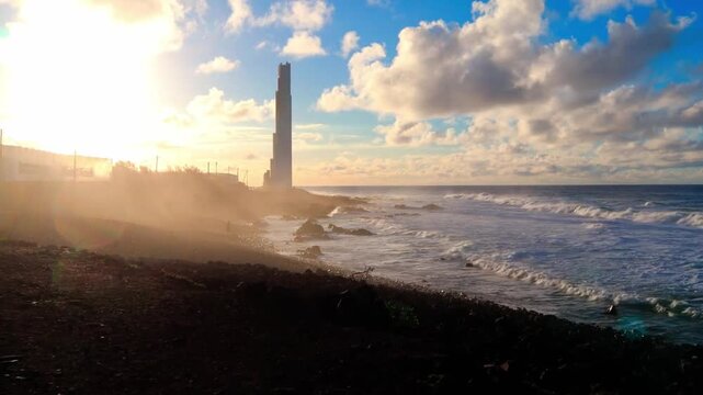 Oil Refinery and Industrial Power Station at Sunset with Tower, Chimneys, Glowing Lights, Smoke, Clouds and Coastal Landscape
