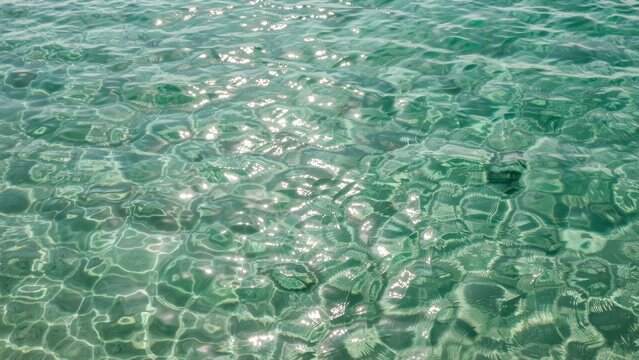 Clear turquoise sea water surface with sun glints and ripples