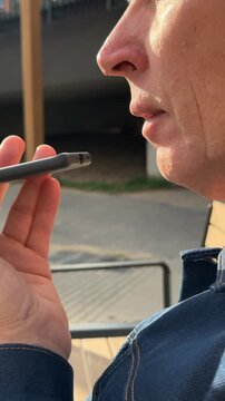 dictating voice note into mobile smartphone application. Mature man holds phone close to mouth to record vocal audio message outside. Modern speech-to-text and sound input technology provides
