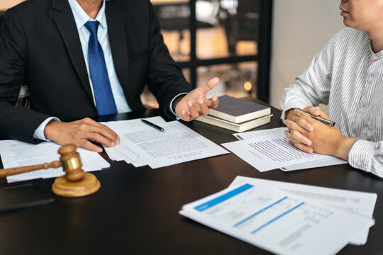 Two people are sitting at a table with papers and a gavel