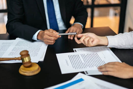 Two people are sitting at a table with papers and a pen