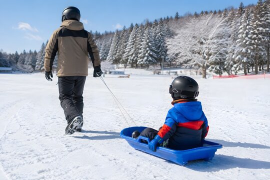 雪遊び広場で子どものそりを引く親