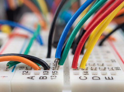 Solderless breadboard with wires inserted during assembly of electronic circuit system.