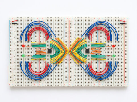 Two white breadboards connected by an intricate, colorful wire design.