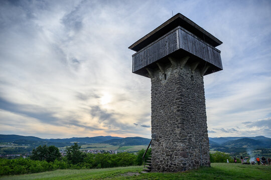 Sun sinking behind thin cloud beside the Vartovka watchtower above Krupina, Slovakia