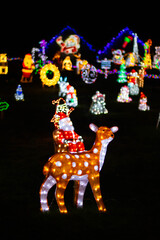 Christmas illuminations, a figurine of a reindeer with Santa on the background of lights © Olha K