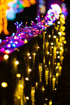 City holiday illuminations, garland stretched along the wall with multi-colored light, vertical shot