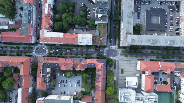 Top-down aerial view of central Maribor, Slovenia, showing historic buildings with red tiled roofs, tree-lined streets, courtyards and urban architecture.