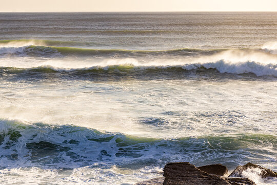 massive waves crashing into rock formations, Walker Bay Nature Reserve, South Africa at sunset