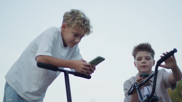 Two Boys Using Smartphones in Skate Park Low Angle Shot