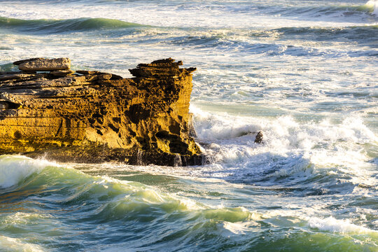 massive waves crashing into rock formations, Walker Bay Nature Reserve, South Africa at sunset