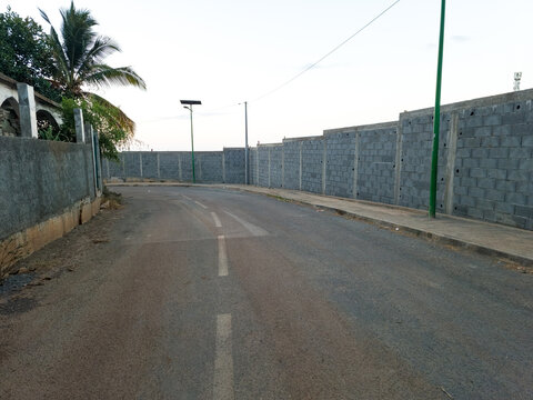 Empty road along a concrete block wall with palm tree at dusk, West Africa