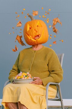 Halloween home portrait of a person with a glowing carved pumpkin head sitting on a porch, cozy and surreal for seasonal decor and cards
