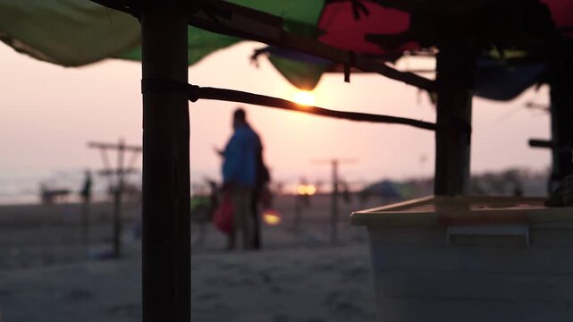 Blurred Sunset on Parang Tritis Beach, Yogyakarta with Silhouetted Figures and Umbrellas