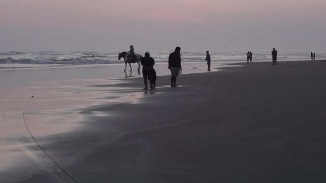 Silhouette of People and Horse at Parang Tritis Beach, Yogyakarta at Sunset