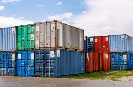 Stacked colorful metal shipping containers in freight storage yard under sunny sky, global trade supply chain and international logistics concept