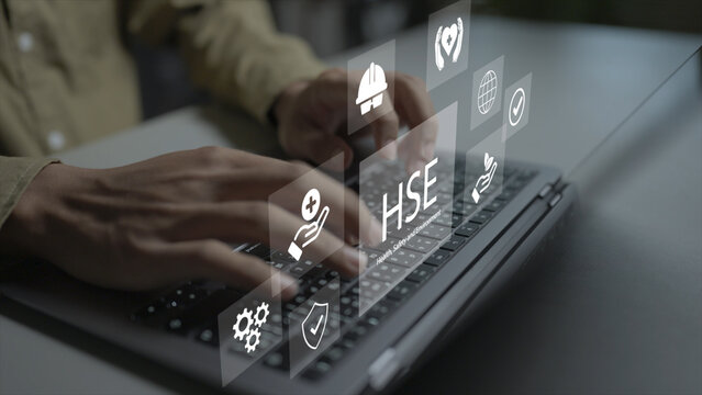 Digital HSE health, safety, and environment platform concept. Person using laptop with hard hat icons, eco leaf and risk audit, corporate sustainability and safety.