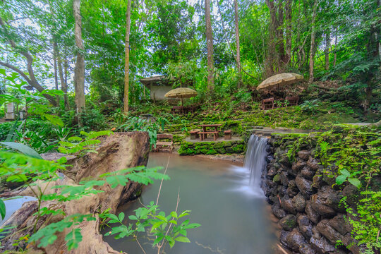 Kathu Dam waterfall water gently flowing down the rocks surrounded by lush green trees flowers and tables Patong on the Island of Phuket Thailand