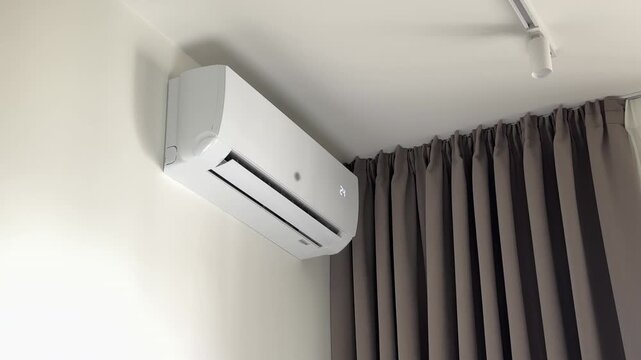Air conditioner activated by a remote control to set temperature to 24 degrees. Wireless controller regulates residential indoor climate system for cooling or heating comfort. White wall mounted split
