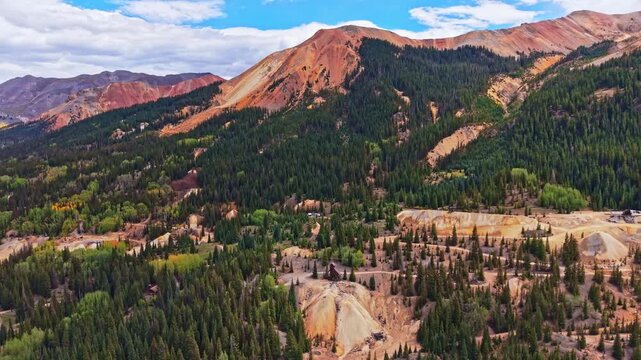 Panoramic aerial view shows historic wooden Yankee Girl Mine headframe amid colorful Red Mountains near Ironton along Million Dollar Highway Colorado