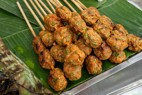 Spicy Thai fried fish cakes Tod Mun Pla on bamboo skewers served on green banana leaf, popular traditional street food