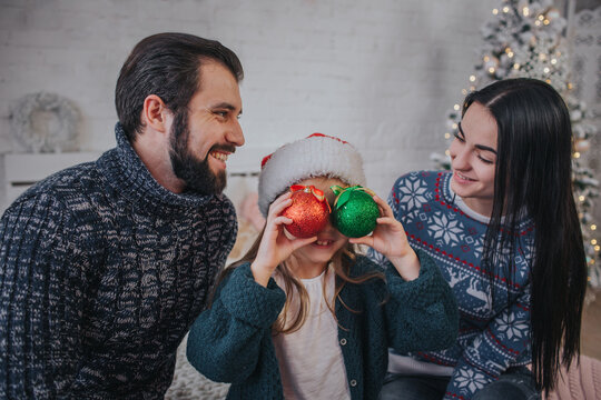 Merry Christmas and Happy New Year . A happy family celebrating holiday at home. Cild girl holding a Christmas ball