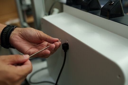 The focus is on the hands of a technician setting up a 3D printer to print a clear white plastic model, using cutting-edge technology and concentrating on specific points within the laboratory.