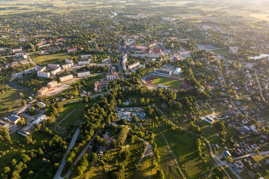 Provincial town with stadium and housing blocks from above. High altitude summer evening drone overview of provincial town with football stadium, athletics track, apartment blocks, private houses.