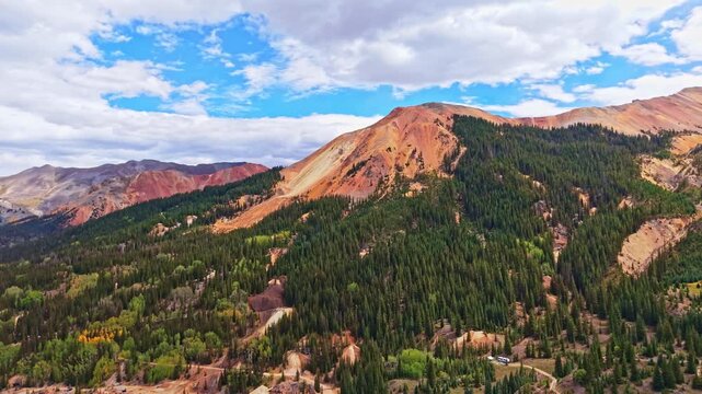 Panoramic aerial view shows historic wooden Yankee Girl Mine headframe amid colorful Red Mountains near Ironton along Million Dollar Highway Colorado