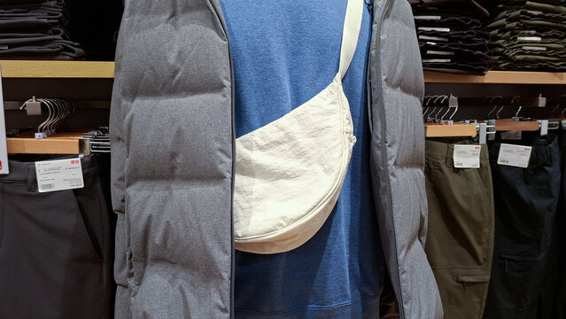 Uniqlo off white round mini shoulder bag with grey puffer jacket slung on mannequin on September 22, 2026 in Bangkok, Thailand.