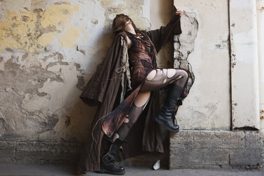 Exhausted woman leaning back on crumbling wall, head thrown back, fatigue and hiding concept