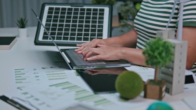 Businesswoman reviewing ESG reports and green business financial charts with a laptop and documents. ESG concept Environmental, Social, and Governance, eco-friendly green building, sustainable