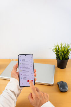 Hands holding smartphone and pressing report message button in email app